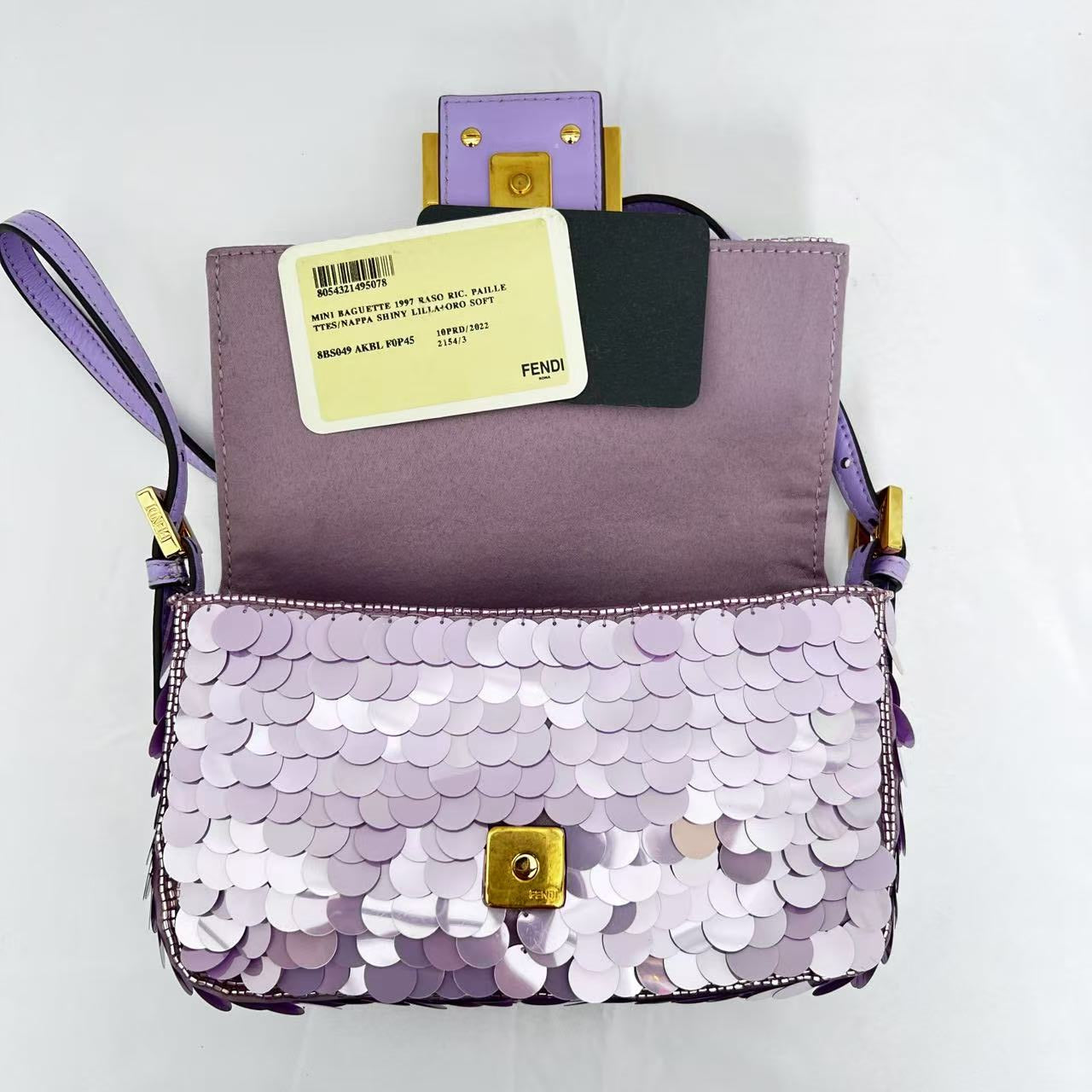 Purple sequin clutch with gold accents on a white background